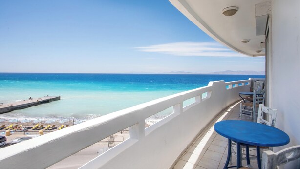 Ein Balkon mit Blick auf das Meer, einen Steg und Strandstühle.