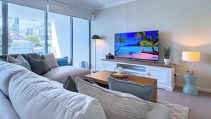 En moderne stue med et stort vindue, et fladskærms-tv og en sofa.