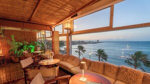 A restaurant with a view of the sea, wooden furniture, and a magazine on the table. - La Terrazza Sul Mare in Rhodes Town (Rhodes)
