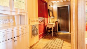 A hallway with a wooden floor, a red door, a white cabinet with drawers, and a chair. - La Terrazza Sul Mare in Rhodes Town (Rhodes)