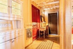 A hallway with a wooden floor, a red door, a white cabinet with drawers, and a chair. - La Terrazza Sul Mare in Rhodes Town (Rhodes)
