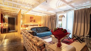 A hotel room with a wooden ceiling, a sofa, a bed, a dining area, and a large window with curtains. - La Terrazza Sul Mare in Rhodes Town (Rhodes)