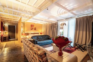 A hotel room with a wooden ceiling, a sofa, a bed, a dining area, and a large window with curtains. - La Terrazza Sul Mare in Rhodes Town (Rhodes)