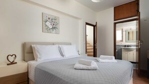 Una cama bien hecha con una colcha acolchada, un adorno con forma de corazón en la mesita de noche y un cuadro en la pared.