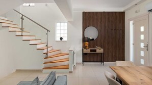 Un interior moderno con una escalera, un comedor y un espejo.