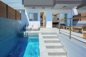 Ein moderner Innenpoolbereich mit großen Glaswänden, einer Treppe zu einer Lounge und einer sichtbaren Küche im Hintergrund.