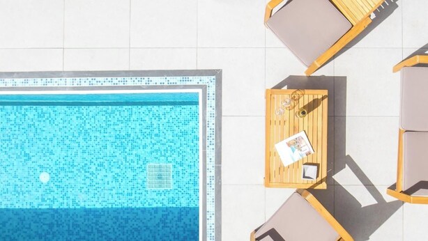 A rooftop pool area with a clear view of the pool, lounge chairs, and a wooden deck. - ArmoniKon Pool Villas - Villa 2 (Rhodes)