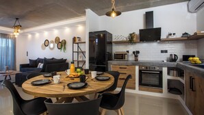 A modern kitchen with a round wooden dining table, black chairs, and a black refrigerator. - ArmoniKon Pool Villas - Villa 2 (Rhodes)
