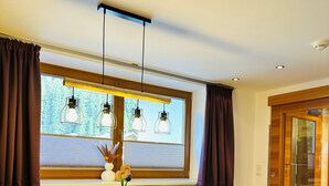 Ein moderner Essbereich mit einem Holztisch, zwei Stühlen, einer Bank und Pendelleuchten.