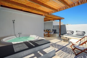 A modern outdoor hot tub area with a wooden pergola, a seating area with a table and chairs, and a view of the surrounding landscape. - ArmoniKon Pool Villas - Villa 3 (Rhodes)