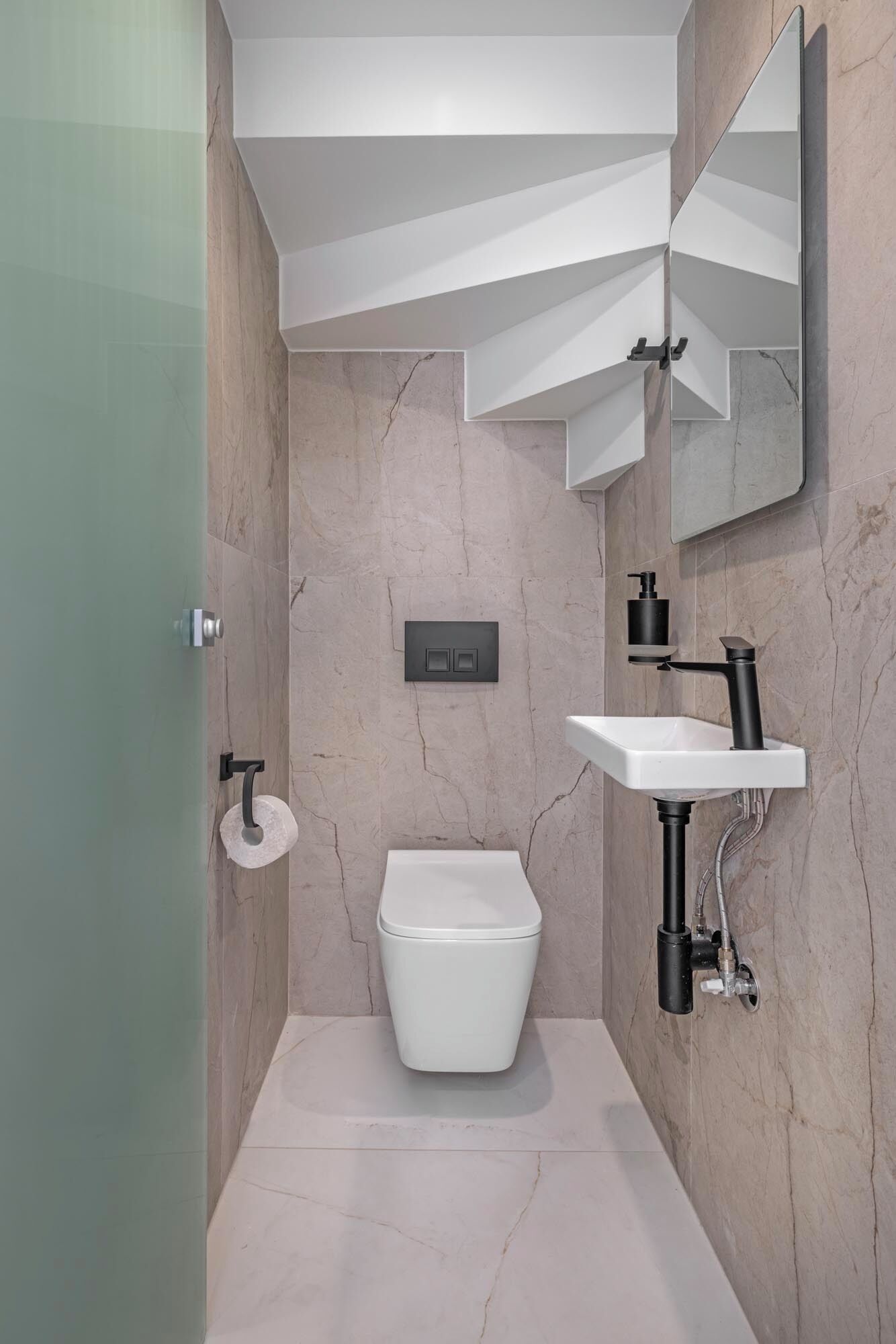 Ein modernes Badezimmer mit Toilette, Waschbecken und Spiegel.