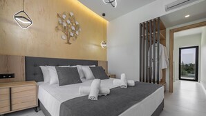 A modern bedroom with a large bed, bedside tables, a wardrobe, and a decorative wall piece. - Tota Suites - Suite 4 (Rhodes)