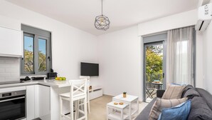 A compact apartment with a kitchenette, a dining area, a living room with a sofa, and a balcony with a view. - Retreat Apartment in Rhodes Town (Rhodes)
