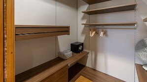 Ein moderner Kleiderschrank mit Holzböden, einer Kleiderstange und einer kleinen schwarzen Box auf einem Regal.