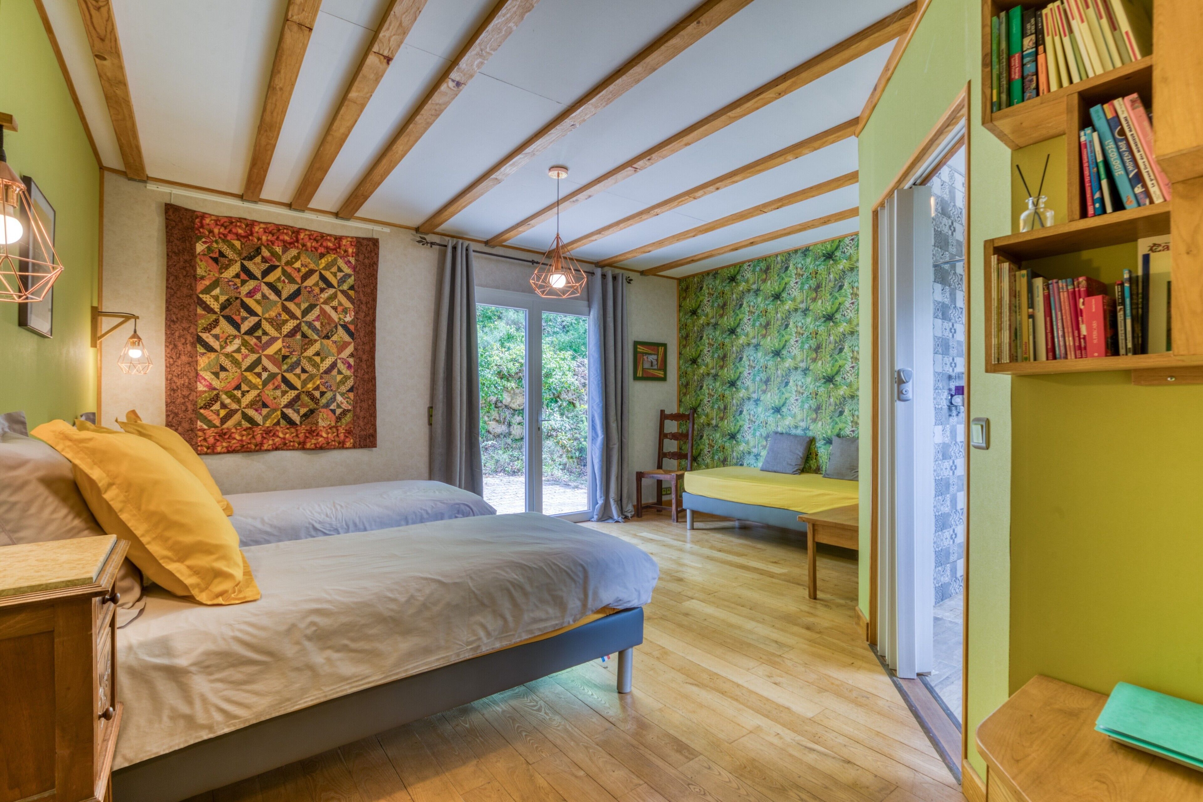 Een slaapkamer met een bed, een sofa, een boekenkast en uitzicht op het buiten.