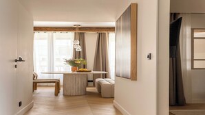 Un intérieur moderne avec un plancher en bois, un coin repas comprenant une table et des chaises, un banc et un grand tableau encadré au mur.