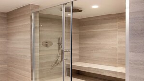 Une douche moderne dotée d’une porte en verre, d’un banc et d’un mur au motif texturé.