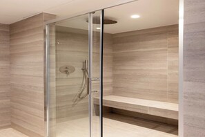 Eine moderne Dusche mit Glastür, Sitzbank und Wand mit Strukturmuster.