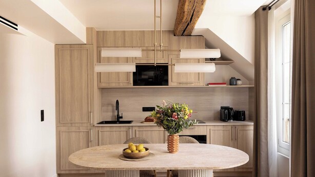 Une cuisine moderne avec des meubles en bois, un four à micro-ondes et un coin repas comprenant une table ronde et un vase de fleurs.