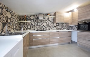 Una cocina moderna con salpicadero estampado, armarios de madera, horno empotrado y estufa a gas.
