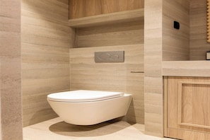 A modern bathroom with a white toilet, a wooden vanity, and a wall-mounted control panel. - Premium Souplex a/c 1BR/4P – Saint-Germain (Paris)