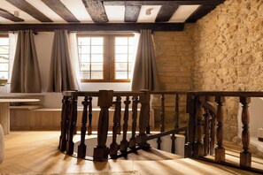 A room with a wooden staircase, stone walls, and a window with curtains. - Premium Souplex a/c 1BR/4P – Saint-Germain (Paris)