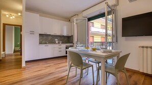 A modern kitchen with white cabinets, a dining table with chairs, and a large window offering a view of a balcony. - 1 bedroom awesome apartment in Recco (Recco)