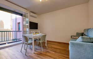 A dining area with a table set for four, a sofa, and a TV mounted on the wall. - 1 bedroom awesome apartment in Recco (Recco)