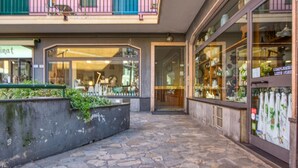 A stone-paved walkway leading to a building with a glass storefront displaying various items. - Lovely apartment in Recco with WiFi (Recco)