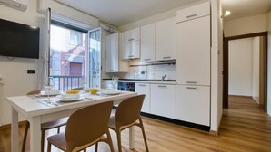 A modern kitchen with white cabinets, a dining table with chairs, and a TV mounted on the wall. - Lovely apartment in Recco with WiFi (Recco)