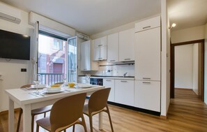 A modern kitchen with white cabinets, a dining table with chairs, and a TV mounted on the wall. - Lovely apartment in Recco with WiFi (Recco)