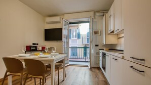 A compact kitchen with white cabinets, a dining table with chairs, and a view through an open door to a balcony. - Lovely apartment in Recco with WiFi (Recco)