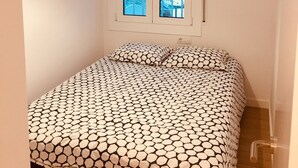 Ein Schlafzimmer mit Bett, einem Fenster mit Blick auf Boote, einer Hängelampe und einer Tür.