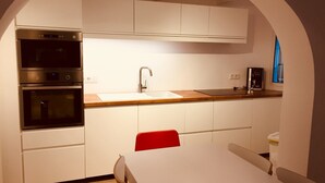 Eine moderne Küche mit weißen Schränken, Edelstahlgeräten, einer Holzarbeitsplatte und einem roten Stuhl.