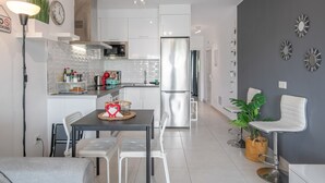 A modern kitchen with white cabinets, a stainless steel refrigerator, and a dining area with a table and chairs. - Vacation Apartment 'Casa Amor Costa Teguise' with Wi-Fi (Costa Teguise)
