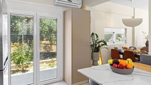 Una cucina moderna con un'ampia finestra, un condizionatore d'aria e un'area pranzo con una ciotola di frutta.