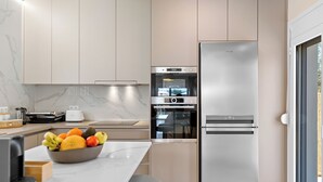 Una cucina moderna con forno integrato, frigorifero e piano di lavoro in marmo.