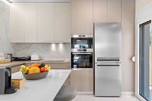 A modern kitchen with a built-in oven, a refrigerator, and a marble countertop. - Villa Charaki VPR, Villa (Rhodes)