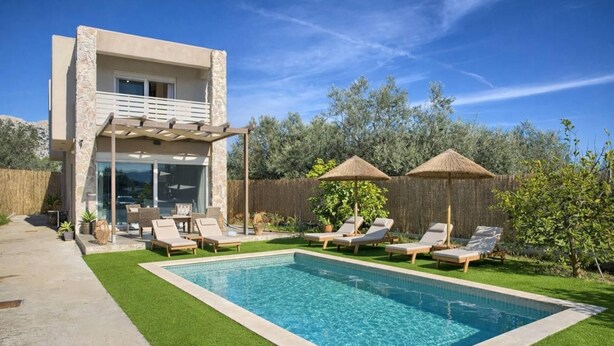 Una casa moderna con piscina, area salotto esterna e facciata in pietra.