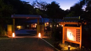 A pathway leading to a traditional Japanese gate with a signboard, surrounded by trees and illuminated by ground lights. - Kaiko Roman NO Yado Kisara (TOBA SHI)