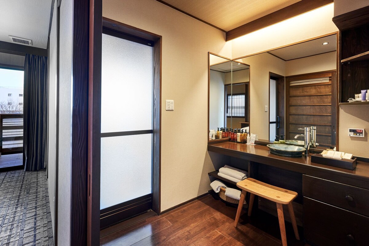 A hotel room with a bed, a bathroom with a sink and mirror, and a view of the outdoors.