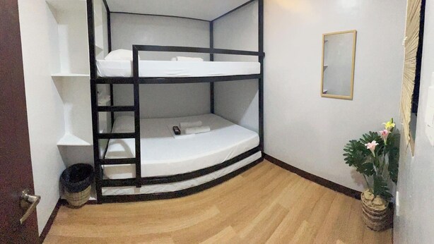 A bunk bed room with a curved headboard, a small mirror, and a potted plant. - Family-Friendly Room in Siargao Air-Conditioned (General Luna)