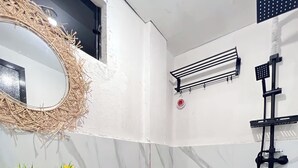 A bathroom with a white sink, toilet, and a mirror with a decorative frame. - Family-Friendly Room in Siargao Air-Conditioned (General Luna)