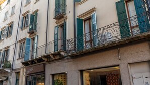 Un edificio con varias ventanas, algunas con contraventanas, y un balcón con barandilla de metal decorativa.