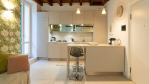 Une cuisine moderne avec des meubles blancs, un tabouret de bar et un plafond en bois.