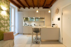 A modern kitchen with white cabinets, a bar stool, and a wooden ceiling. - New Bridge House - Domus Verona (Verona)