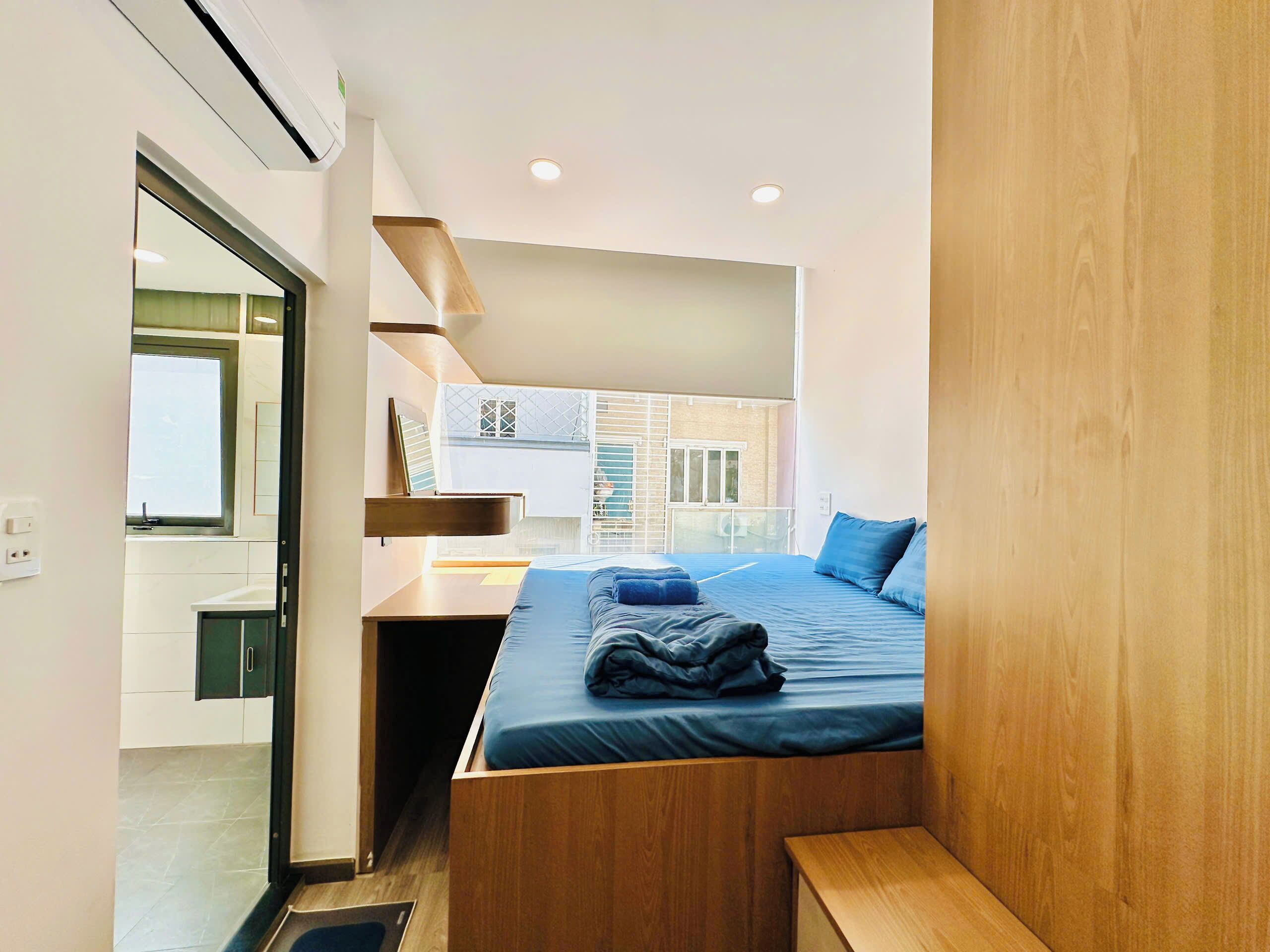 Ein modernes Schlafzimmer mit Bett, Holz-Kopfstück und Blick ins Freie.