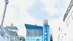 A building with a prominent 'Loftic' sign, a gated entrance, and a visible outdoor seating area. - Loftic Apartments - Pink Church (Ho Chi Minh City)