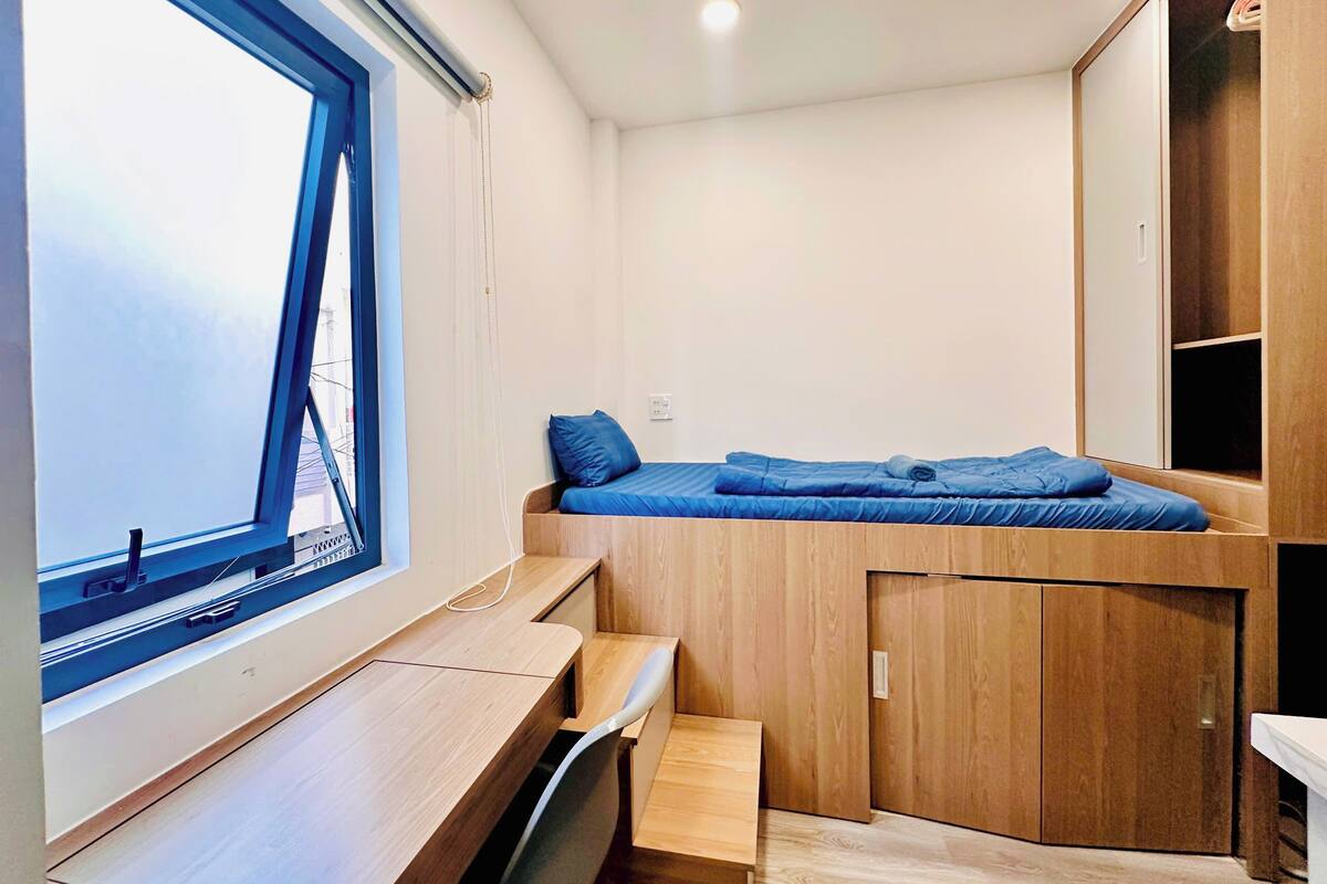 Habitación pequeña con una cama nido, un escritorio y una ventana.