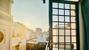 A view through a window with a grid pattern, overlooking a cityscape with buildings and a clear sky. - Loftic Apartments - Pink Church (Ho Chi Minh City)